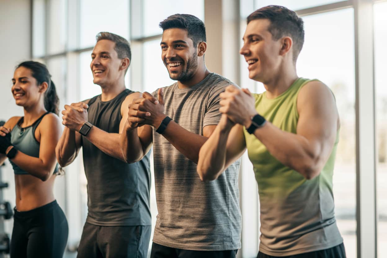 Well Fitness Company Happy, fit diverse people working out together in a modern gym, bright natural light, showing motivation and energy."